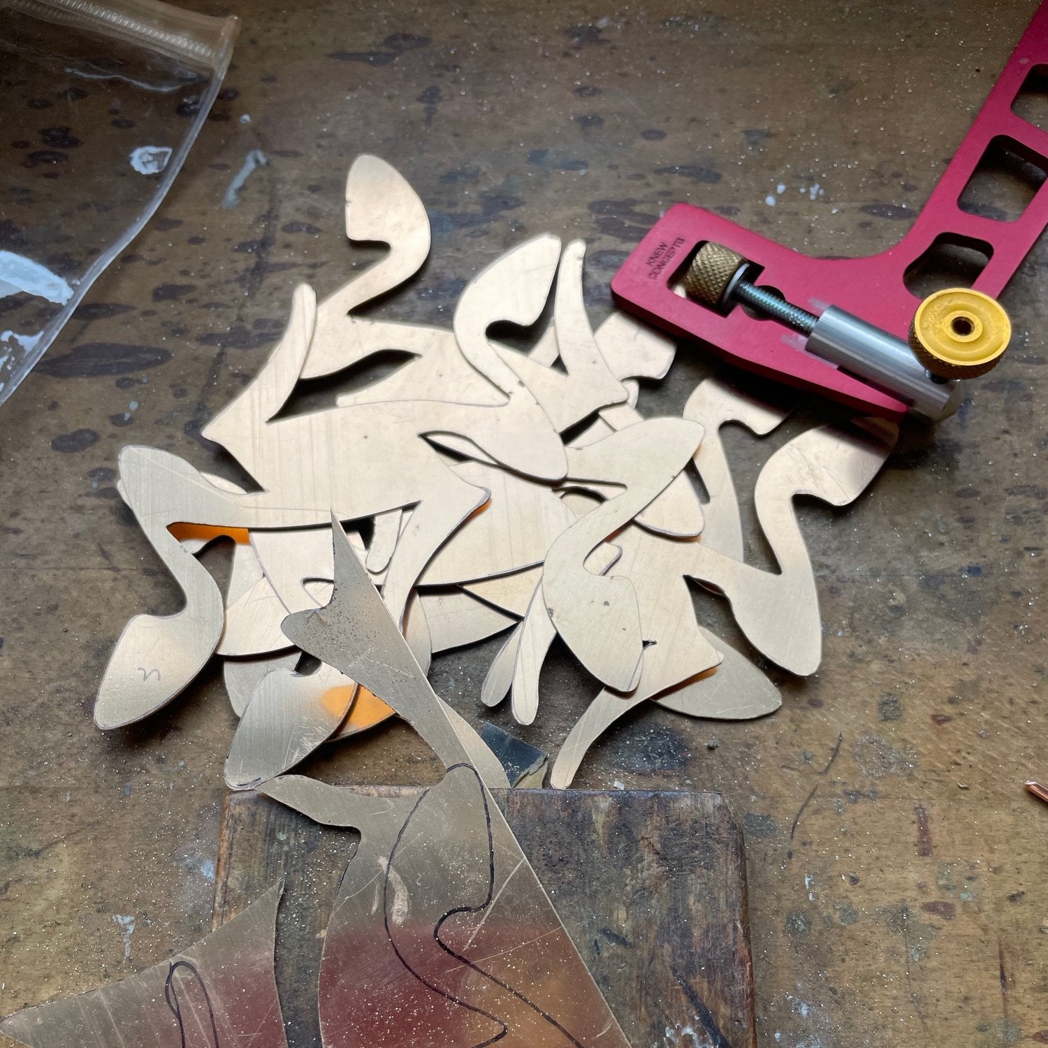 Many pierced silver pieces and jewellery saw on workbench